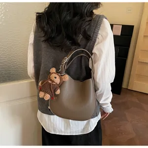 Detailed view of the dark brown lychee texture leather bucket bag with a cute bear charm