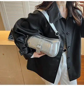 Detail of silver metallic baguette bag with pleated texture and buckle strap on leather jacket
