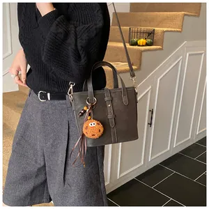 Détail du sac seau gris foncé en cuir mat avec un charmant pendentif biscuit