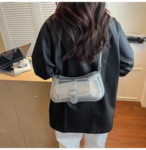 Metallic silver baguette bag with vintage texture and buckle detail worn by a model