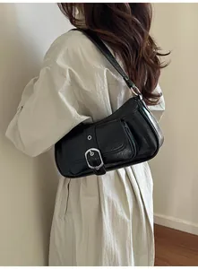 Detail shot of a black PU leather baguette bag featuring a silver buckle on a side-shoulder view