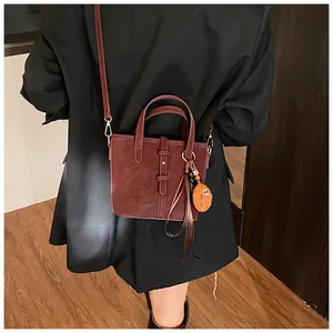 Détail du sac seau bordeaux avec bandoulière et pendentif en peluche mignon