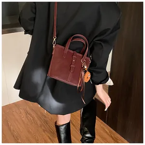Détail du sac seau vintage bordeaux avec boucle décorative et pendentif biscuit en peluche