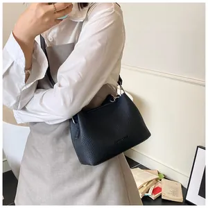 Détail du sac seau en cuir noir grainé avec lettrage élégant et bandoulière fine