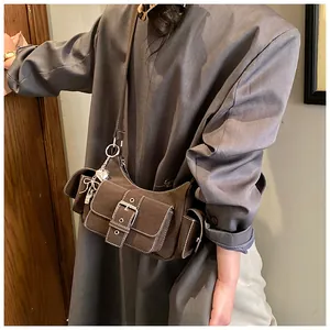 Détail du sac baguette vintage marron avec boucles métalliques et breloque cœur