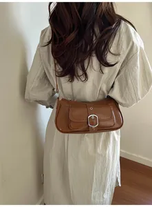 Detail of brown leather baguette bag featuring silver buckle and adjustable shoulder strap