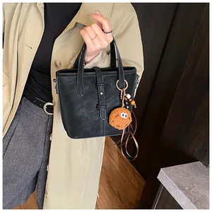 Détail du sac seau noir avec texture vintage et joli porte-clés biscuit marron