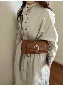 Detail of caramel vintage leather crossbody bag with silver buckle and front flap pocket