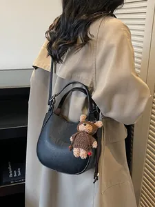 Minimalist black lychee leather bucket bag with cute bear charm and adjustable strap