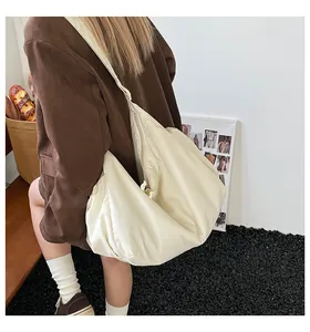 Femme portant un sac cabas en toile crème au design croissant souple et large bandoulière