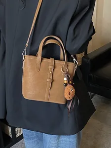 Sac seau marron rétro avec charm en peluche porté avec un costume noir et un jean décontracté