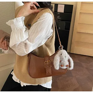Brown vintage baguette bag with gold buckle and plush rabbit charm detail
