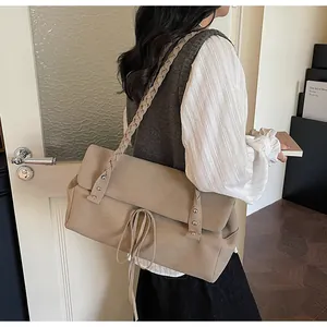 Dettaglio della borsa tote in pelle scamosciata kaki con borchie e tracolla intrecciata