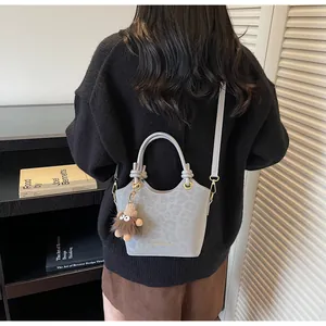 Détail du sac seau gris avec motif léopard, poignée nouée et breloque monstre en peluche