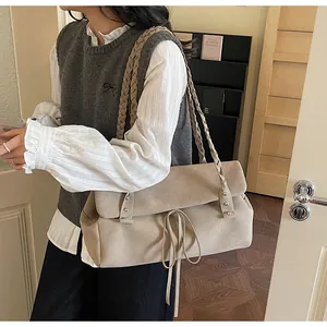 Dettaglio della borsa tote beige in scamosciato con tracolla intrecciata e fiocco decorativo