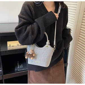 Détail du sac seau à motif léopard avec lettrage doré et breloque ours en peluche