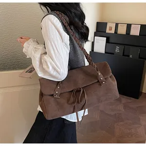 Dettaglio di borsa tote in pelle scamosciata marrone con tracolla intrecciata e fiocco