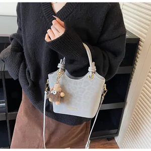 Détail du sac seau gris avec texture léopard et breloque monstre en peluche sur sangle