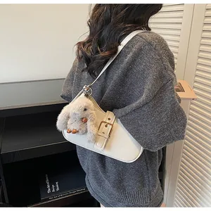 Chic beige baguette bag with metallic buckle and plush rabbit charm on a stylish model