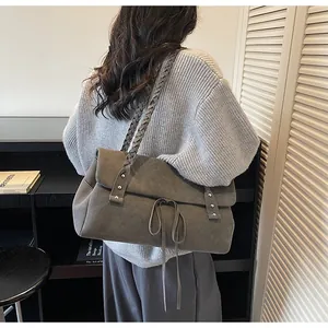 Dettaglio della borsa tote grigia in pelle scamosciata con tracolla intrecciata