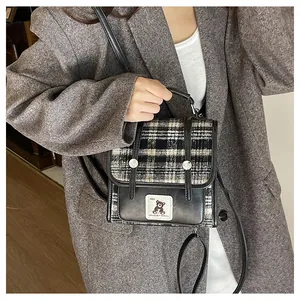 Détail du sac cabas à carreaux montrant l'écusson ours et les lanières en cuir chic
