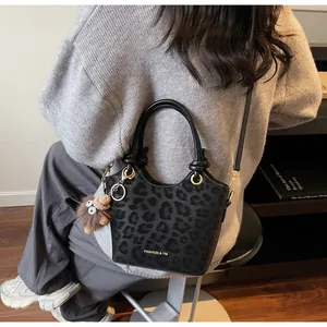 Détail du sac seau léopard avec poignées rondes et breloque monstre en peluche marron