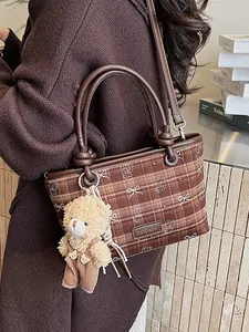 Sac fourre-tout à carreaux marron avec breloque ours et bandoulière en cuir sur modèle