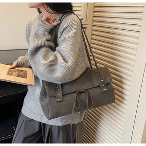 Dettaglio della borsa tote grigio scuro con tracolla intrecciata e morbida texture scamosciata