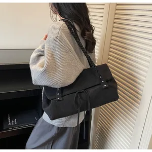 Dettaglio borsa shopper nera con tracolla intrecciata e design con lacci alla moda