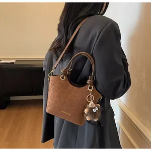 Gros plan du sac seau en cuir embossé léopard marron avec breloque peluche et détails dorés