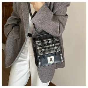 Vue détaillée du sac bandoulière rétro à carreaux avec garniture en cuir noir et patch