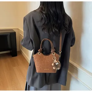 Détail d'un sac seau marron à texture léopard avec charm monstre en peluche doux