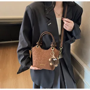 Gros plan du sac seau marron à texture léopard avec charm monstre et logo doré