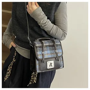 Détail du motif à carreaux rétro et des coutures en cuir sur le petit sac carré