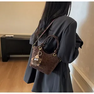 Détail du sac seau à imprimé léopard avec breloque peluche porté à l'épaule pour femme