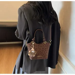 Détail du sac seau léopard marron avec anneaux métalliques et breloque monstre en peluche
