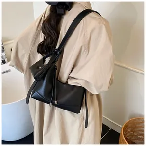 Détail du sac baguette en cuir grainé noir avec lignes courbes et lanières de côté