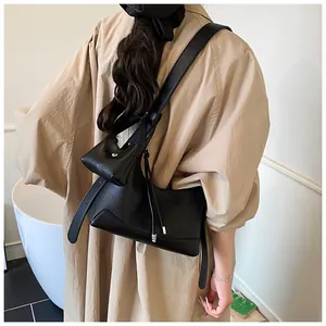 Détail du sac baguette en cuir grainé noir avec une petite pochette sur la bandoulière