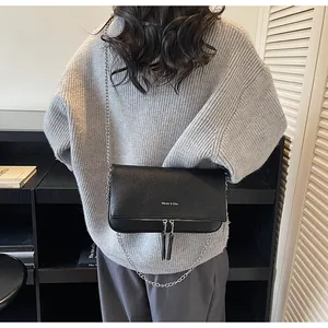 Détail du sac baguette noir en cuir grainé avec chaîne argentée et pompons à franges