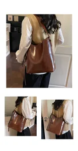 Detailansicht der braunen Lackleder-Einkaufstasche mit Markenlogo und Nahtdetail