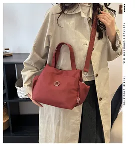 Détail du sac seau en nylon rouge vin montrant le tissu et la large bandoulière