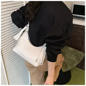 Sac baguette hobo en cuir grainé blanc porté à l'épaule pour un style chic au quotidien