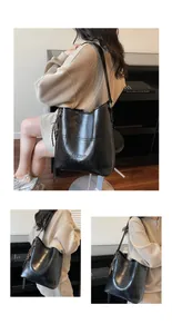 Detail der schwarzen Wachsleder-Eimertasche mit Logo-Prägung und Quastenanhänger