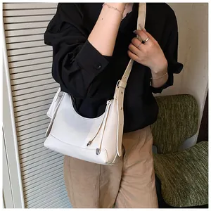 Détail latéral du sac baguette blanc texture litchi avec bandoulière et nœud