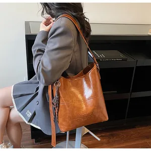 Detail of vintage brown leather tote bag with embossed logo and striped side ribbon
