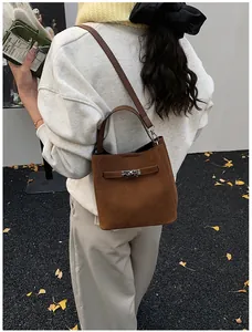 Détail macro du sac seau en daim marron avec fermeture élégante à verrou tournant argent