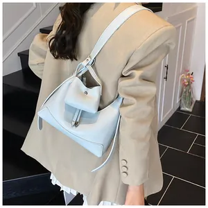 Détail du sac baguette en cuir grainé bleu clair avec bandoulière réglable sur tailleur