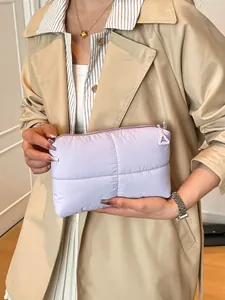Pochette trapuntata lilla chiaro con motivo a croce, tenuta da modella in trench
