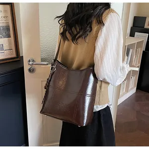 Detail view of large dark brown leather tote bag with glossy finish and bottom metal rivets