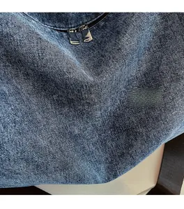 Detail of the blue denim fabric texture and silver double metal zipper on the tote bag
